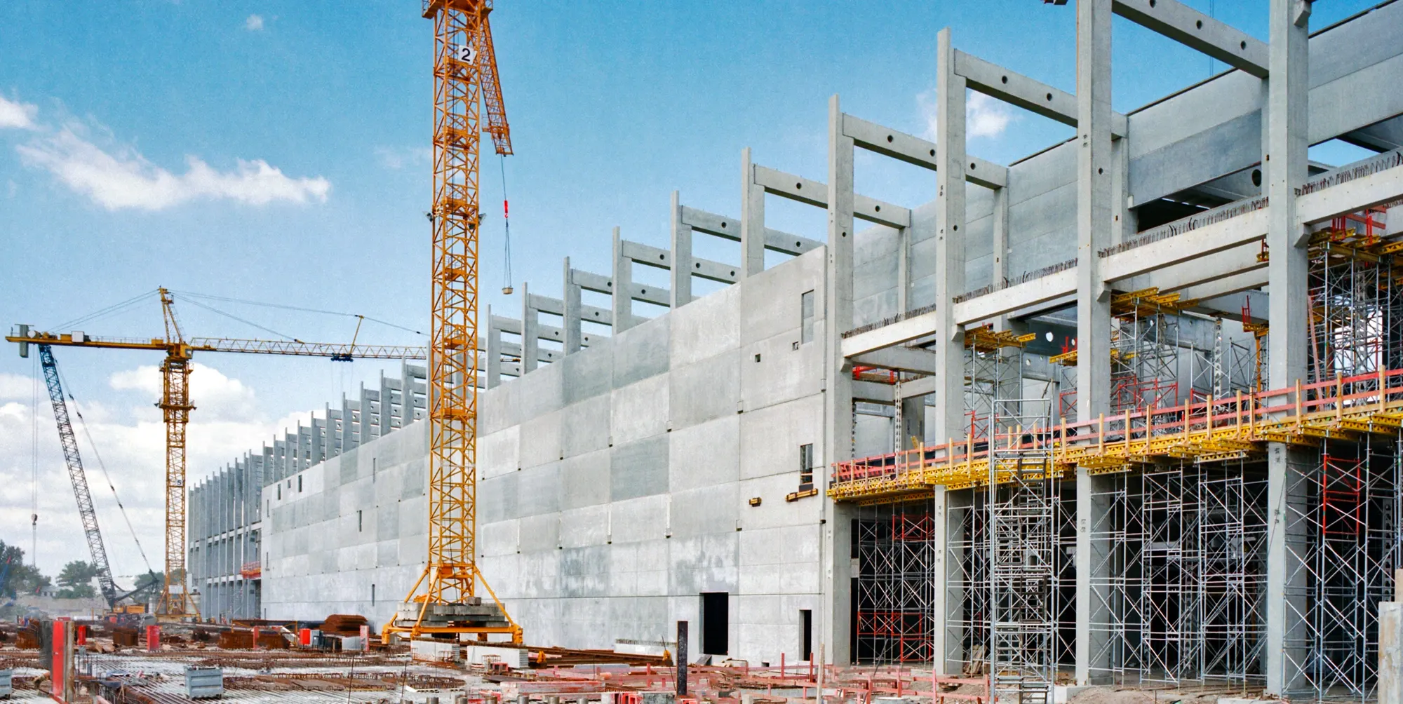 Budowa dużej hali z prefabrykatów betonowych, dźwigi wieżowe i rusztowania